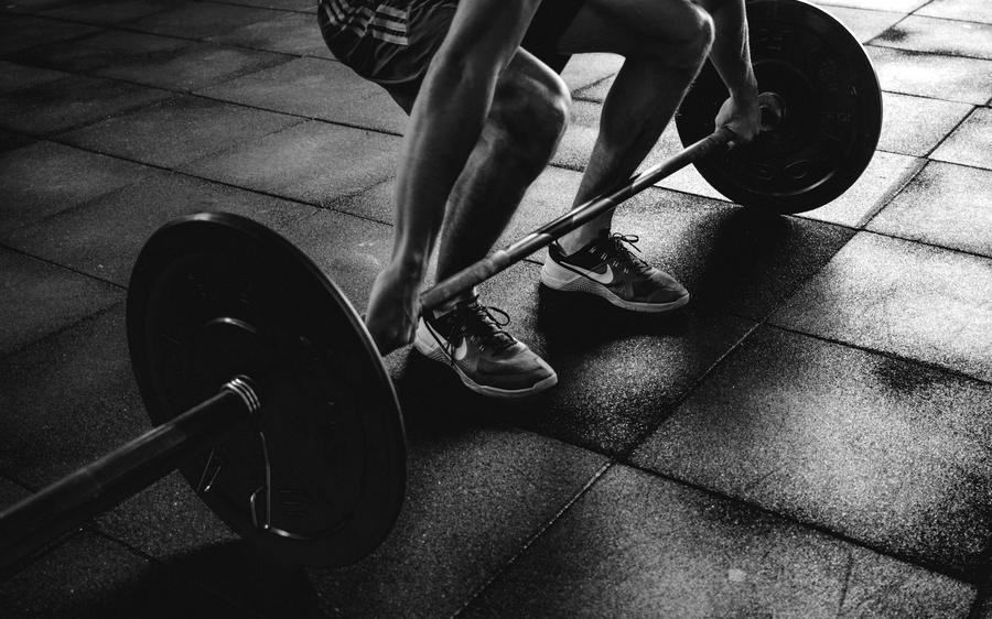 Barbell mid-lift in a dark gym